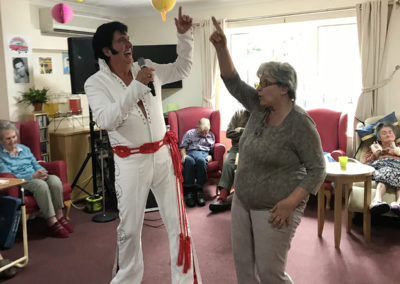 An Elvis performer singing and dancing with a resident at Lulworth House Residential Care Home