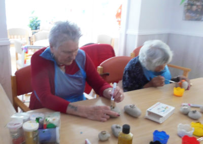A group of residents painting rocks with bright paint at Woodstock Residential Care Home