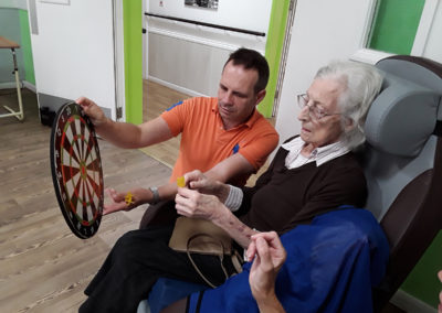 Abbotsleigh resident playing magnetic darts with the help of a staff member