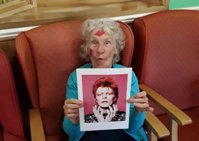 Princess Christian resident wearing face paint and holding up a picture of David Bowie as Ziggy Stardust