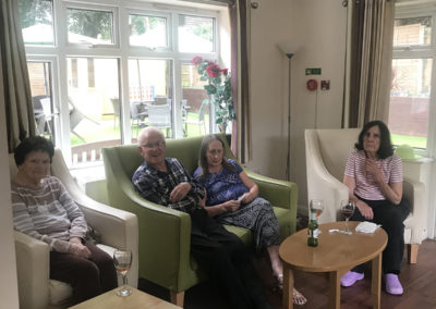 Lulworth House residents relaxing with a glass of wine or a beer in the conservatory