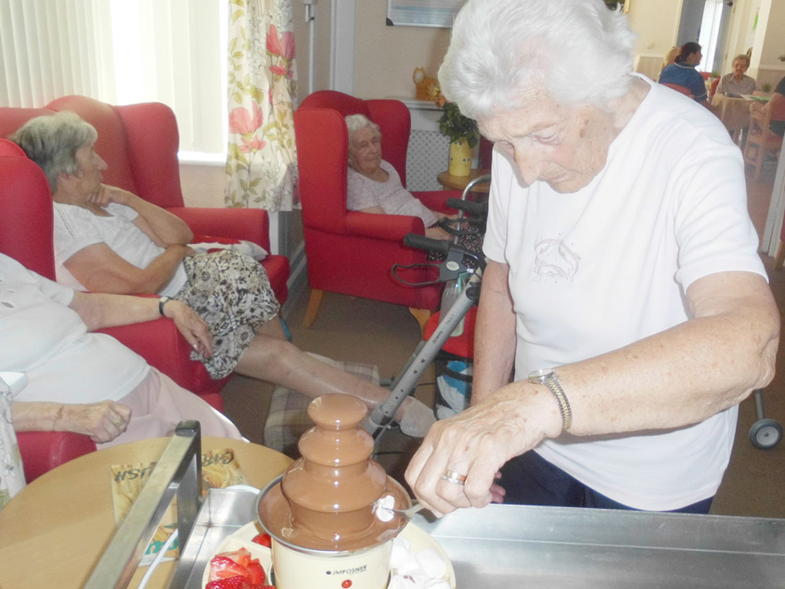 Woodstock lady dipping a marshmallow into a chocolate fountain