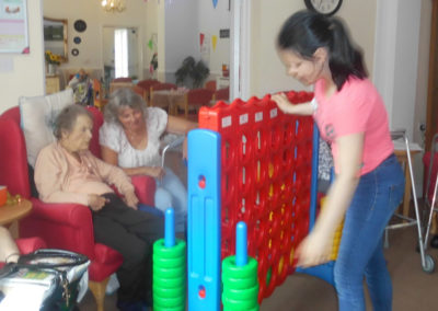A resident and family member playing giant Connect Four with a visiting child