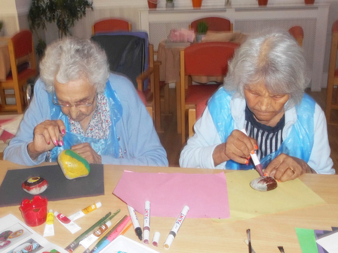 Two lady residents sat at a table painting rocks together