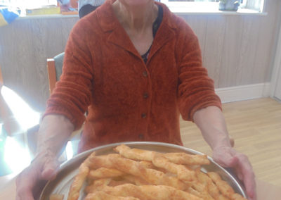 A resident at The Old Downs Residential Care Home showing off a plate of home cooked cheesy sticks