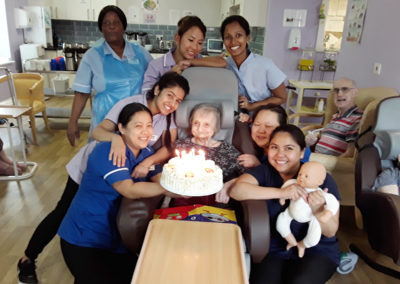 A resident surrounded by staff with a birthday cake