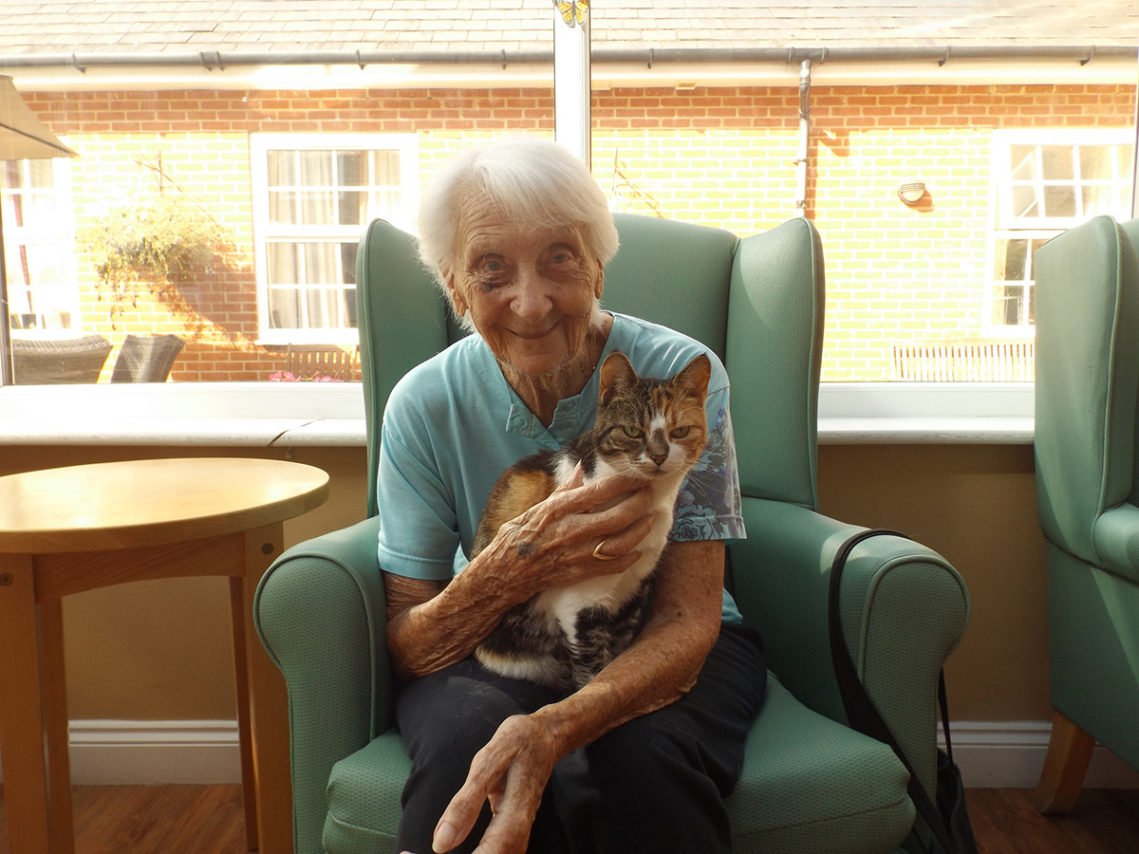 A female resident cuddling a cat on her lap