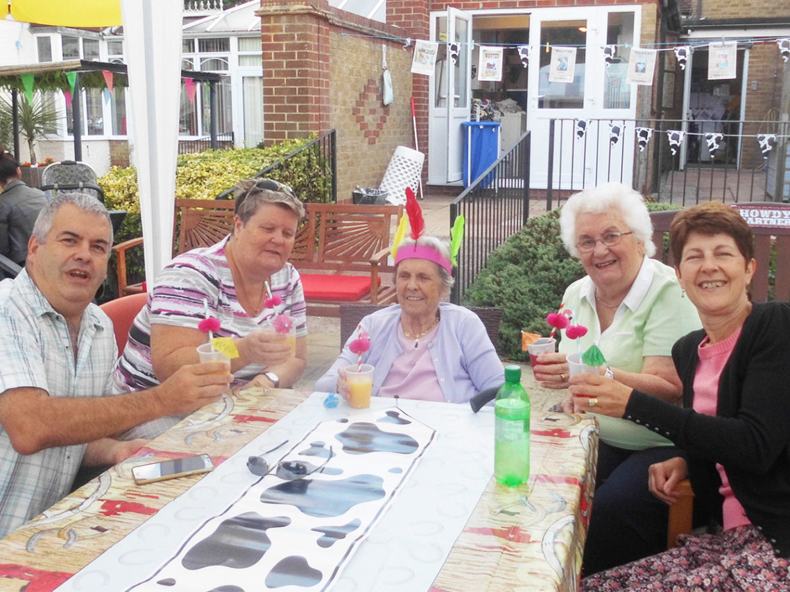 Residents and family seated together enjoying mocktails at a summer barbecue