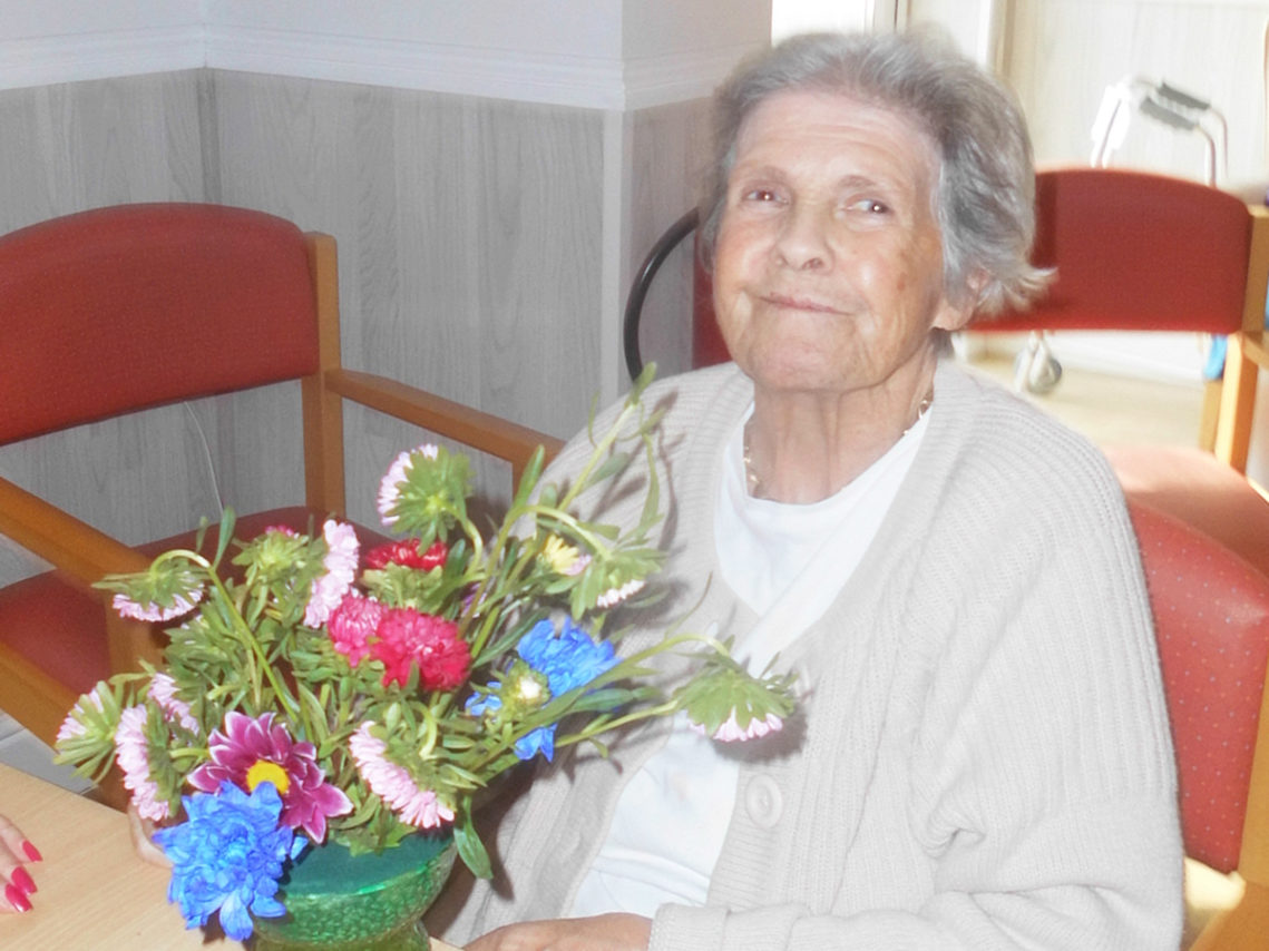 A happy smiling resident at Woodstock about to do some flower arranging