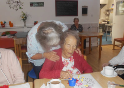 A female Woodstock resident enjoying a cup of tea as she creates a colourful flower picture