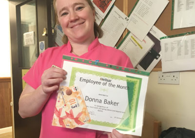 Employee of the month Donna Baker holding up a certificate and shopping vouchers