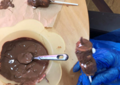 Residents at Meyer House making chocolate covered marshmallow lollipops