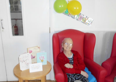 Female Woodstock resident smiling for the camera with her birthday cards, balloons and banner