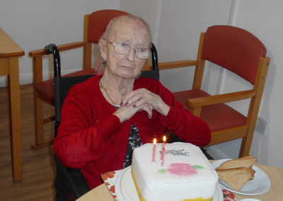 Female Woodstock resident looking thoughtful as she blows out candles on her birthday cake