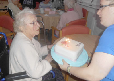 Lady resident at Woodstock Residential Care Home receiving a birthday cake