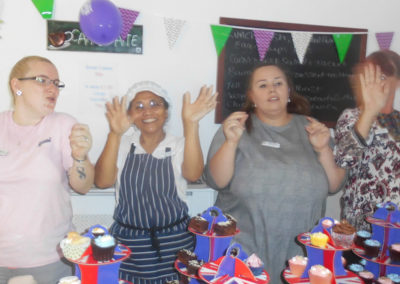 The Woodstock staff team dancing to music behind the table of cakes