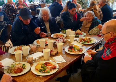 Lukestone Care Home residents around a cafe table enjoying Christmas lunch together at Polhill Garden Centre