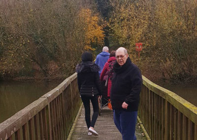 Lukestone Care Home residents walking over a bridge in a park