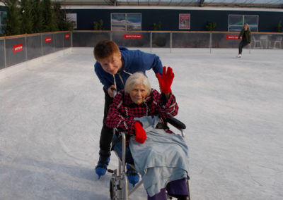 A lady resident and carer on the ice at Ruxley Manor Garden Centre's ice rink