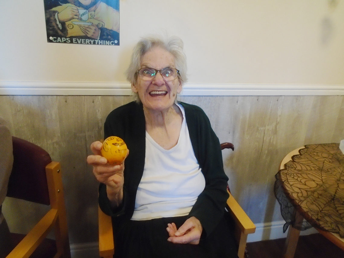 Lady resident at The Old Downs Residential Care Home with a decorated orange for Halloween