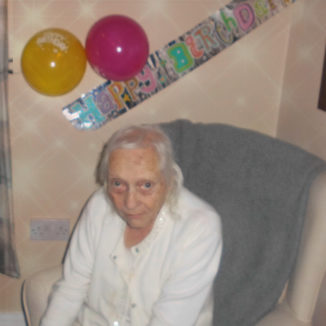 Lady resident from Woodstock Residential Care Home with her birthday banner and balloons