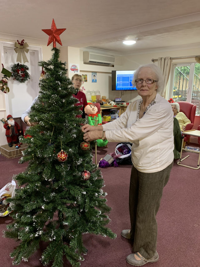 Lulworth House Residential Care Home resident by a Christmas tree, decorating it