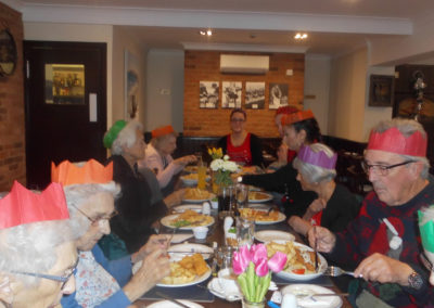 Residents, friends and staff from Woodstock Residential Care Home around a table at Marino's restaurant, eating a festive fish and chip lunch