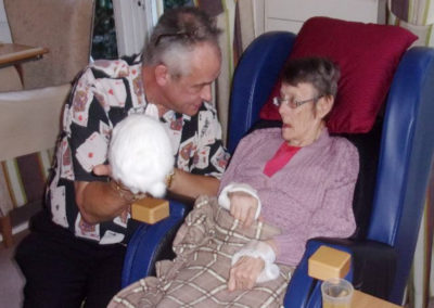 Mark the magician showing a white rabbit to a resident in the lounge at Loose Valley Care Home