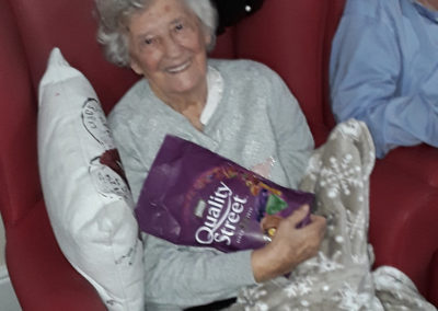 A Lulworth House residents smiling at receiving a box of Quality Street
