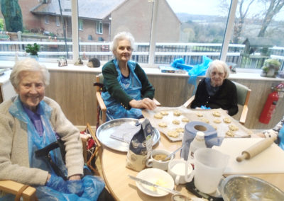 Lady residents at The Old Downs Residential Care Home, sat around a table of cookie ingredients