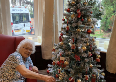 Lulworth House Residential Care Home lady resident decorating a Christmas tree