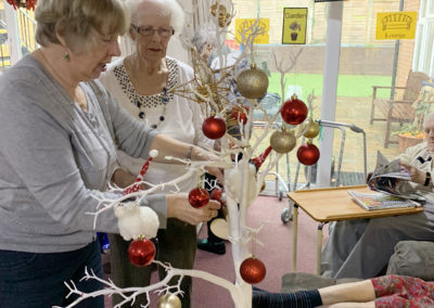 Lulworth House Residential Care Home residents decorating a white table top Christmas tree