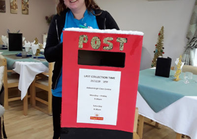 The handmade Abbotsleigh Christmas Post Box with staff member Poppy