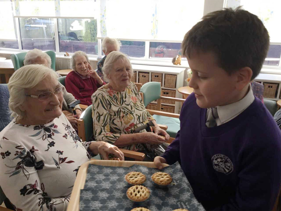 Pupil from Our Lady of Hartley Catholic primary school, offering mince pies to the residents of The Old Downs Residential Care Home
