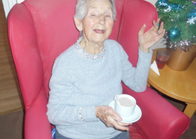 Lady resident at Woodstock Residential Care Home, sitting in a chair, enjoying a hot chocolate