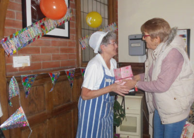 The Assistant Chef at Woodstock Residential Care Home receiving birthday presents from a staff member on her 80th birthday