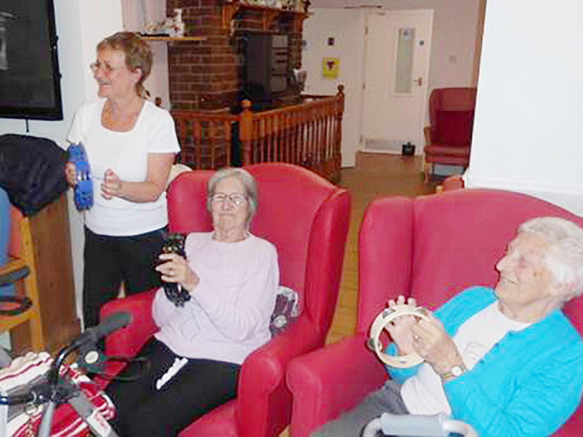 Two ladies from Woodstock Residential Care Home seated with tambourines, during an exercise class