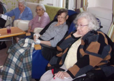 Loose Valley Care Home residents seated in their lounge together, being entertained by a singer