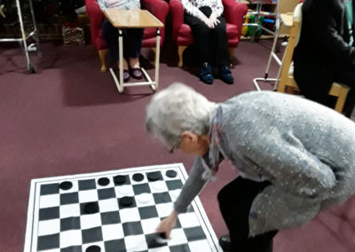 A lady resident placing a piece down on a giant draughts board