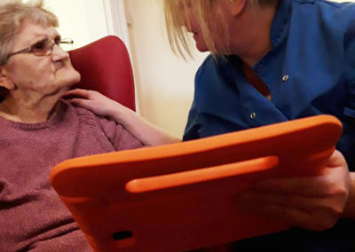 A Lulworth House lady resident and staff member with an interactiveMe tablet