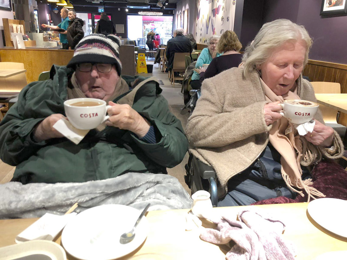 Lady and gentleman resident sitting together in Costa enjoying a to chocolate