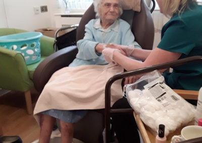 Carer giving a lady resident a relaxing hand massage