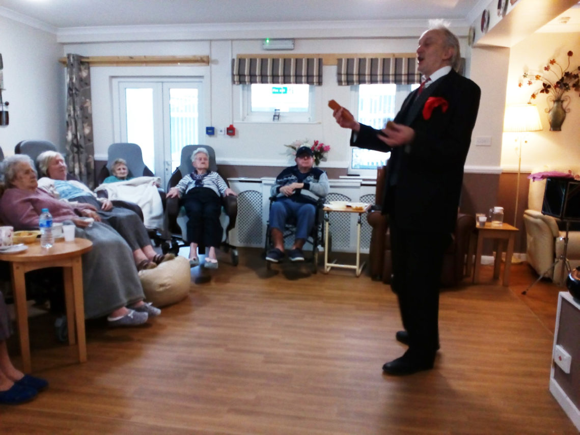 Residents at Meyer House Care Home watching a magician perform in their lounge