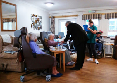 Residents at Meyer House Care Home enjoying a magician doing slight-of-hand magic in their lounge