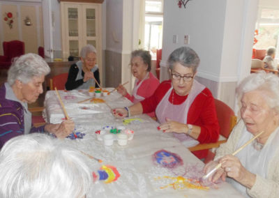 A group of Woodstock lady residents sat around a table painting on fabric