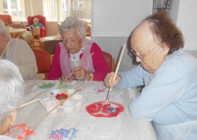 Two Woodstock lady residents sat at a table painting on fabric
