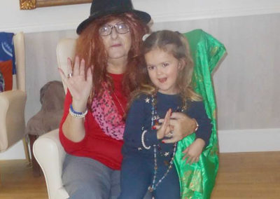 A Woodstock lady resident with fancy dress props sitting with a young girl from Squirrels Nursery