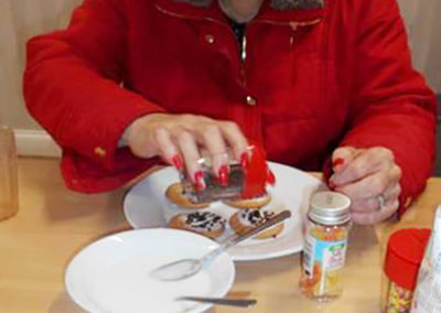 Lady resident at Woodstock Residential Care Home decorating an iced biscuit with sprinkles