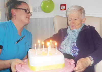 Resident at Woodstock Residential Care Home receiving her birthday cake with candles