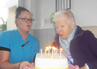 Resident at Woodstock Residential Care Home blowing out candles on her birthday cake